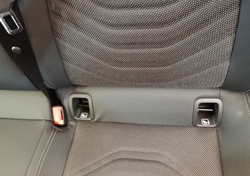 Gros plan sur la banquette arrière noire de la Mercedes Classe A avec fixation Isofix et ceinture rouge visible.