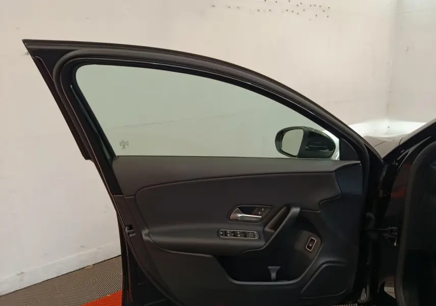 Vue intérieure de la porte avant gauche noire d'une Mercedes Classe A 250 e Business Line 2022, avec commandes électriques.