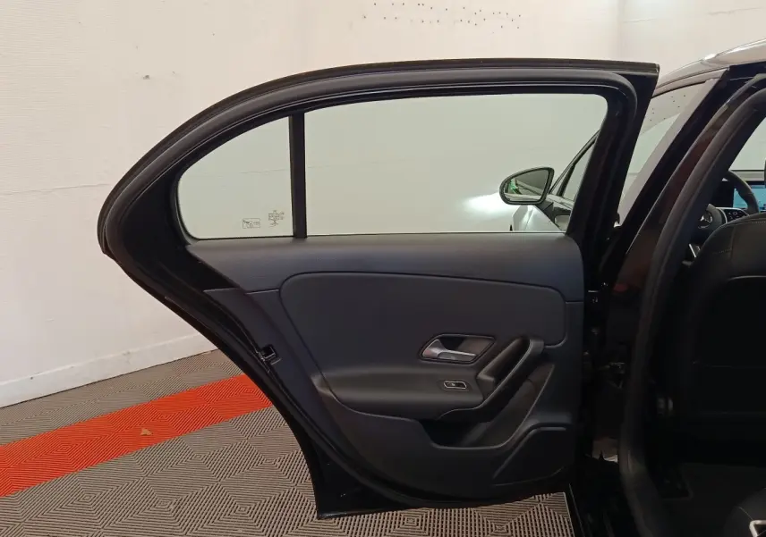 Vue intérieure de la porte arrière gauche ouverte d’une Mercedes Classe A 250 e Business Line noire, avec garniture noire.