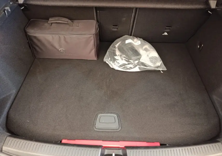 Coffre ouvert de Mercedes Classe A 250 e Business Line noir, vue plongeante avec sac Mercedes et accessoires dans le coffre.