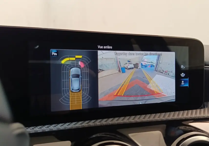 Écran tactile intérieur montrant la caméra de recul et les capteurs de stationnement d'une Mercedes Classe A noire.