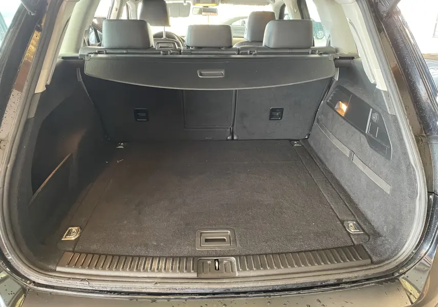 Coffre ouvert d'un Volkswagen Touareg noir 2012, vue arrière montrant un espace de chargement propre et bien aménagé.