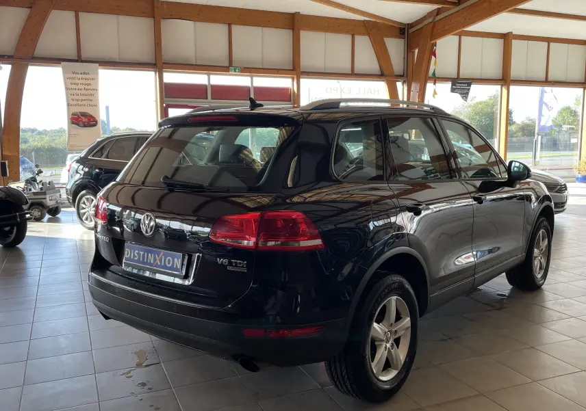Vue 3/4 arrière droite d'un Volkswagen Touareg noir 2012 V6 TDI 204ch dans un showroom lumineux.