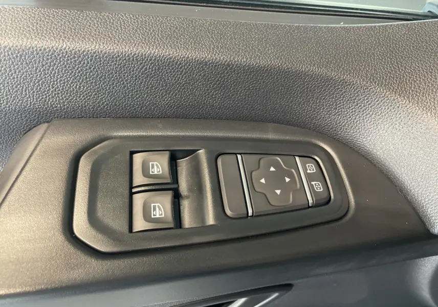 Commandes électriques des vitres et rétroviseurs sur la portière côté gauche d'un Renault Trafic Fourgon gris Comète.
