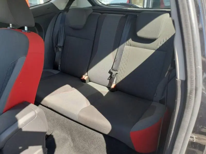 Vue intérieure arrière droite de la Ford Fiesta noire, banquette 3 places en tissu noir avec détails rouges sur les sièges avant.