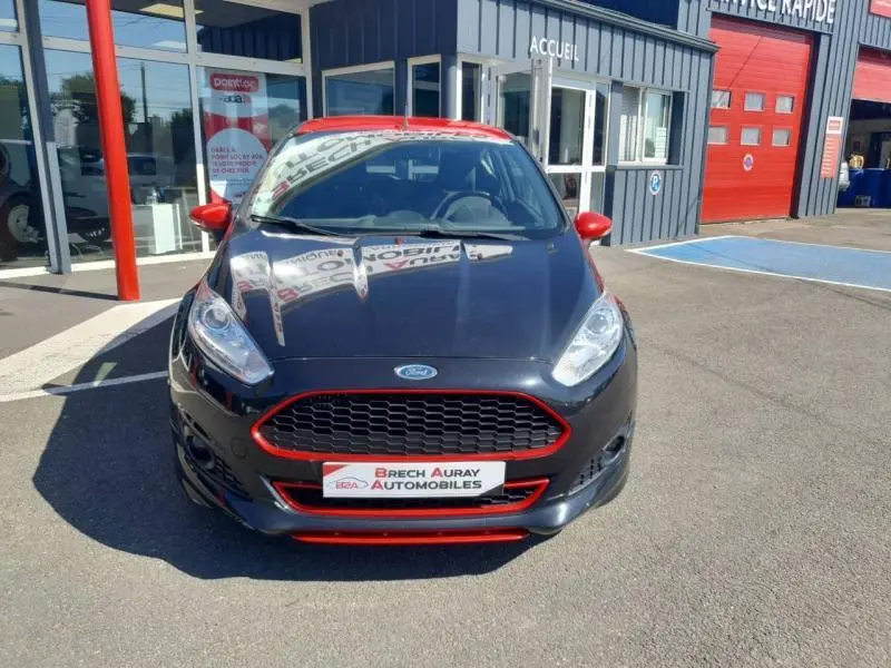 Ford Fiesta 2015 noir vue de face, avec détails rouges sur calandre, rétroviseurs et toit, devant un garage.