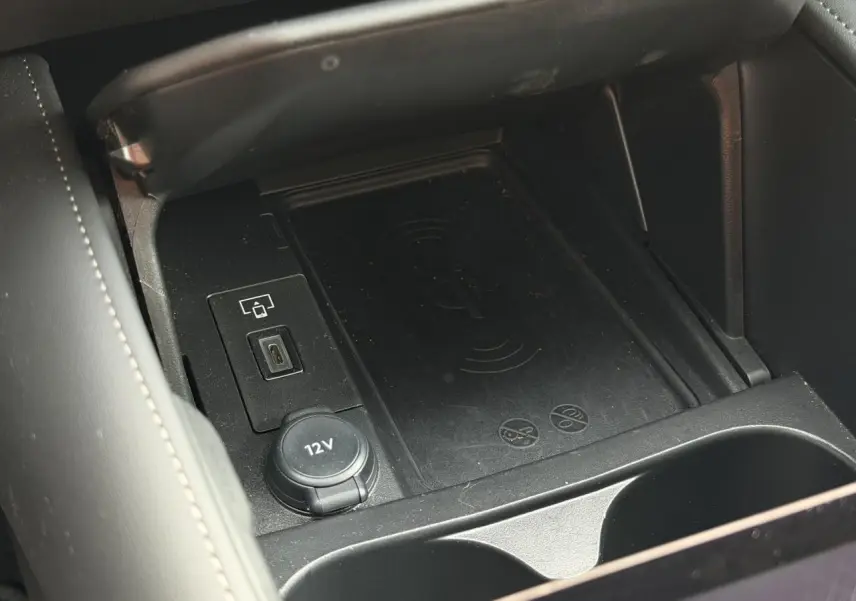 Vue rapprochée de la console centrale noire du DS4 2025 avec chargeur sans fil et prise 12V visible.