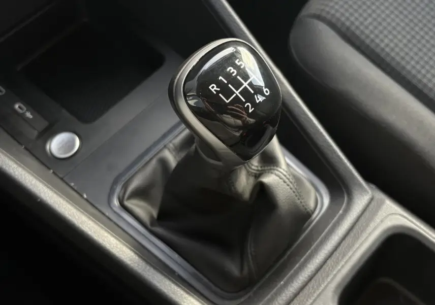 Le levier de vitesses manuel noir du Volkswagen Caddy 2024 vu en gros plan depuis l'intérieur côté conducteur.