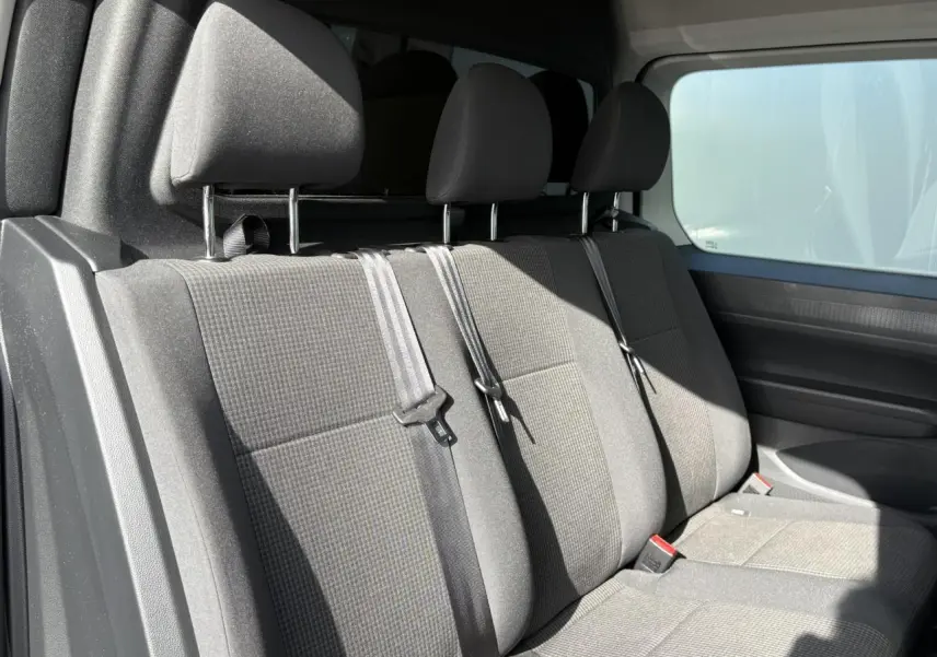 Vue intérieure côté droit montrant la banquette arrière grise avec trois appuie-têtes et ceintures de sécurité du Volkswagen Caddy 2024.