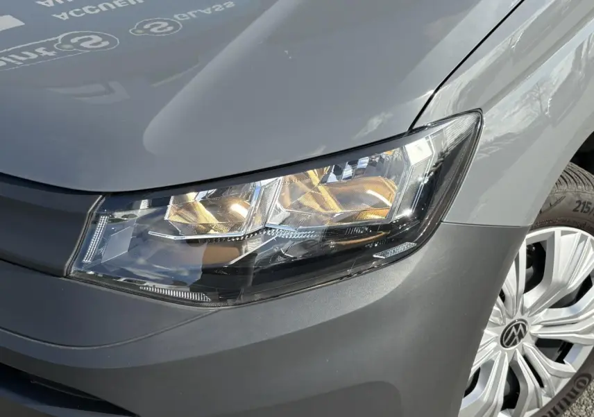 Gros plan sur l'avant droit du Volkswagen Caddy 2024 Pure Grey, mettant en valeur le phare et la jante alu.