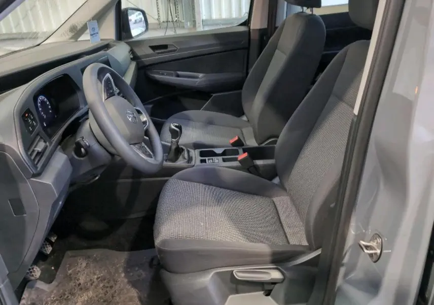Vue intérieure côté conducteur du Volkswagen Caddy Maxi 2024 en Pure Grey, montrant sièges et tableau de bord.