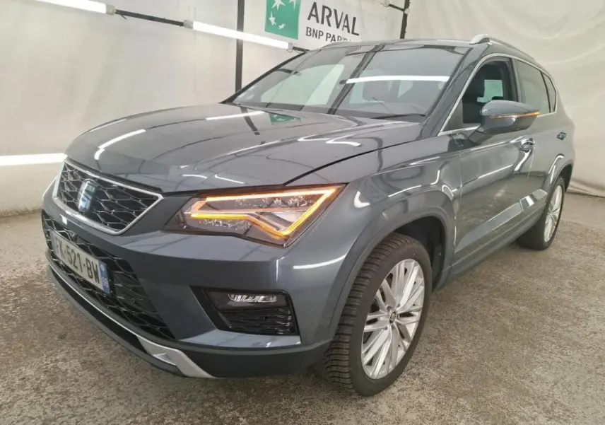 SEAT Ateca gris clair en 3/4 avant droit avec phares LED allumés et jantes alliage 18 pouces visibles.