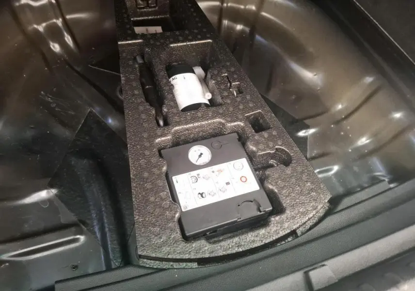 Vue rapprochée du coffre du SEAT Ateca gris clair 2019 montrant le kit anti-crevaison rangé dans la roue de secours.