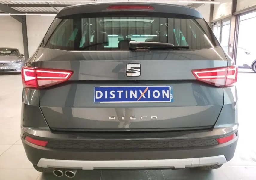 Vue arrière d'un SEAT Ateca gris clair avec double sortie d'échappement et feux arrière LED allumés dans un garage.