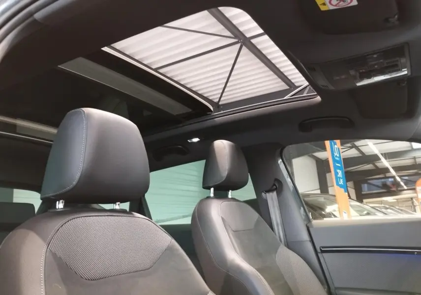 Vue intérieure avant du SEAT Ateca gris clair avec toit ouvrant panoramique et sièges en alcantara brun.