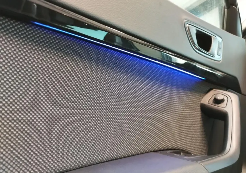 Détail de la porte avant droite du SEAT Ateca gris clair avec éclairage d’ambiance bleu et commande de rétroviseur.