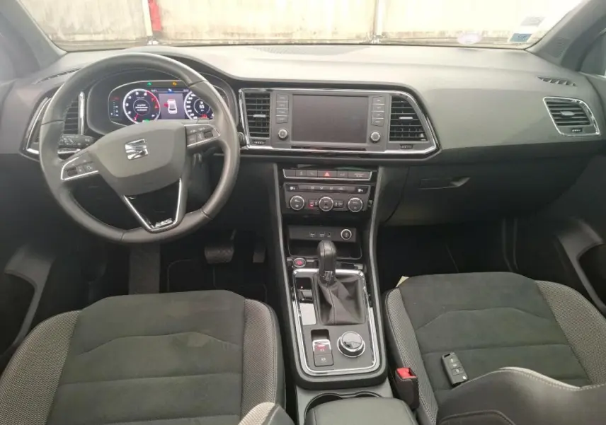 Vue intérieure avant du tableau de bord et console centrale du SEAT Ateca gris clair avec volant multifonctions et écran tactile.