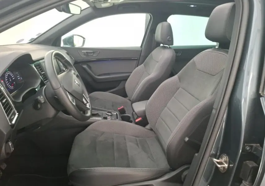 Vue intérieure côté conducteur du SEAT Ateca gris clair, mettant en valeur les sièges en alcantara et le grand toit ouvrant panoramique.