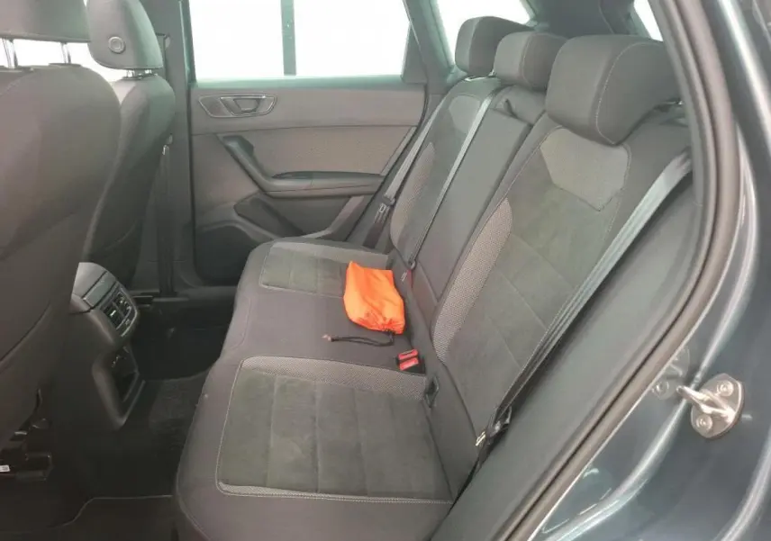 Vue côté droit de la banquette arrière en alcantara brun avec un sac orange posé, intérieur du SEAT Ateca gris clair.