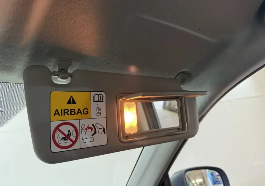 Détail du pare-soleil côté conducteur du Suzuki Vitara noir 2022 avec miroir éclairé et avertissement airbag.