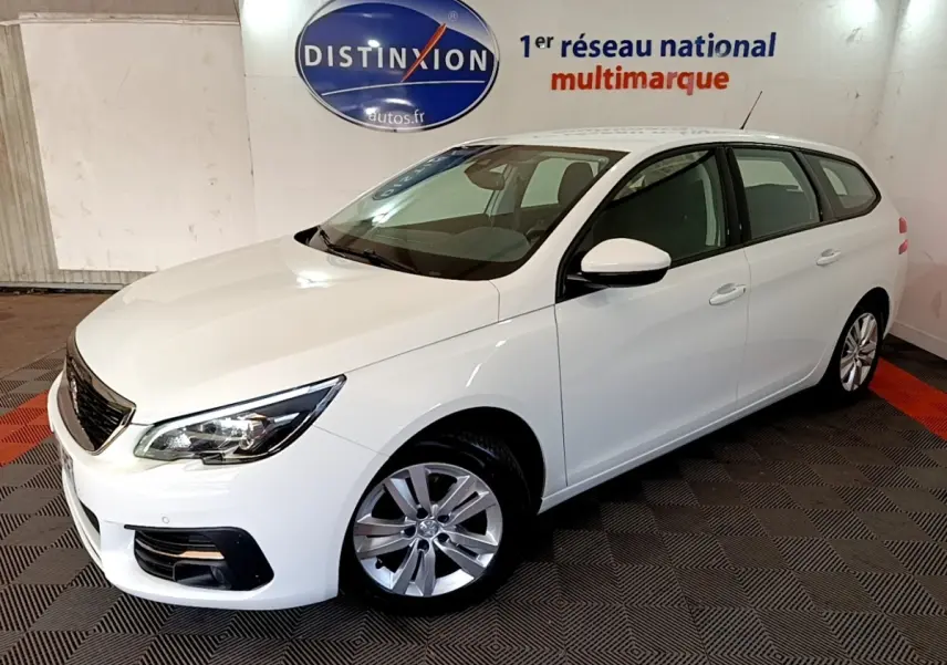 Peugeot 308 break blanc vue 3/4 avant droit dans un showroom avec logo Distinxion en arrière-plan.