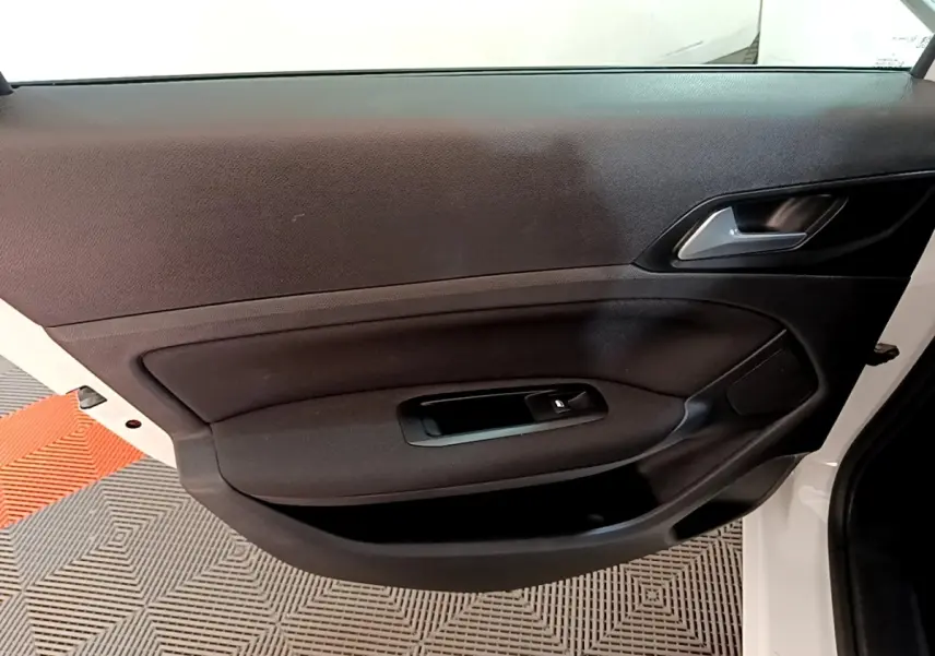 Vue intérieure de la porte avant droite blanche de la Peugeot 308 avec commande de vitre électrique et poignée argentée.