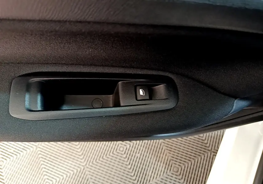 Poignée intérieure de porte arrière droite noire sur Peugeot 308 blanche, avec bouton de verrouillage.