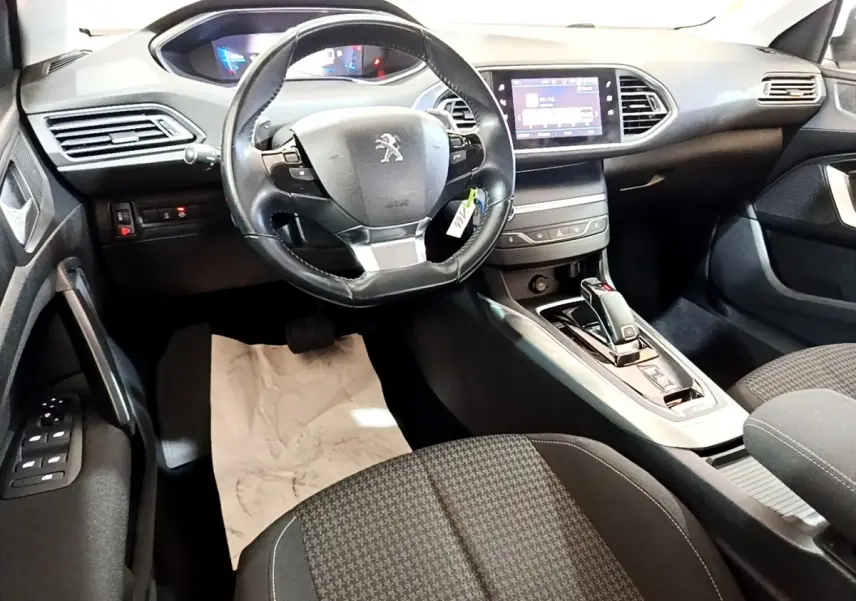 Intérieur noir de la Peugeot 308 2021, vue avant centrée sur le volant cuir et l’écran tactile du tableau de bord.