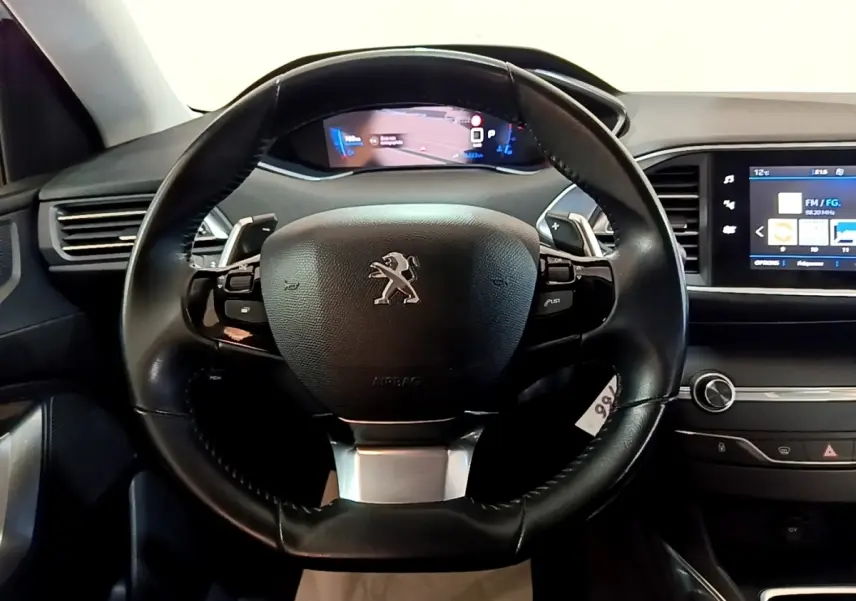 Vue centrée sur le volant cuir noir de la Peugeot 308 avec tableau de bord numérique et écran tactile latéral.