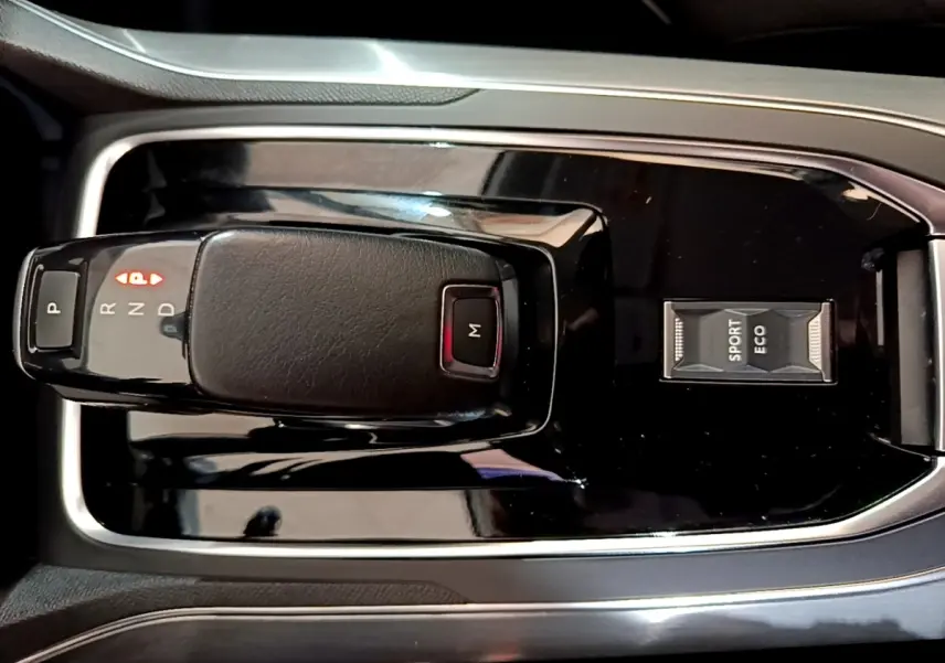 Gros plan sur la console centrale noire de la Peugeot 308 blanche, avec levier de vitesses automatique et sélecteur modes Sport/Eco.