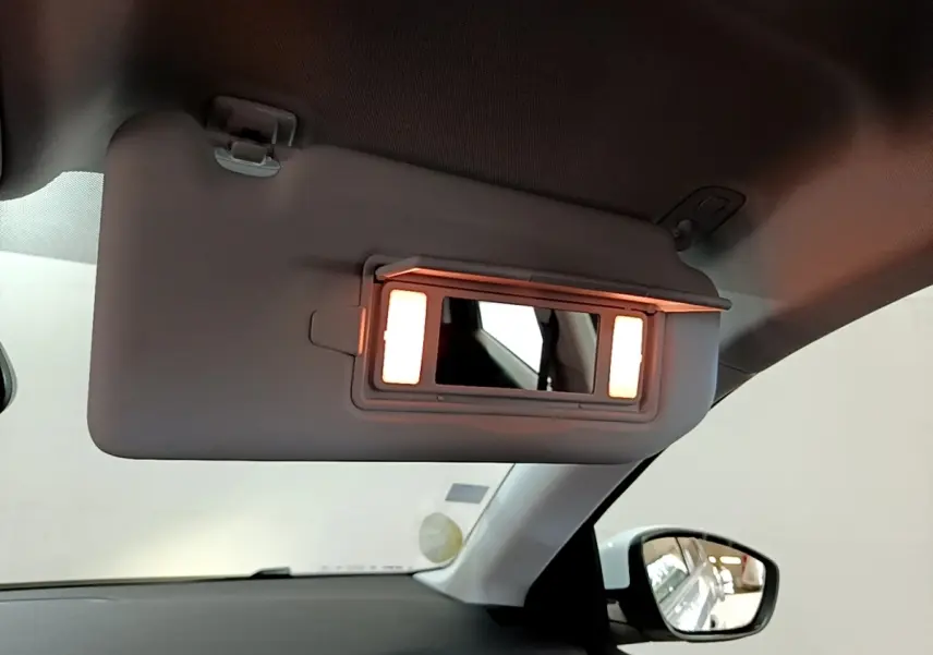 Détail du pare-soleil côté conducteur avec miroir éclairé dans l’habitacle d’une Peugeot 308 blanche.