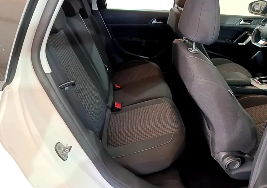 Vue intérieure côté gauche montrant la banquette arrière et les sièges avant noirs d'une Peugeot 308 blanche.