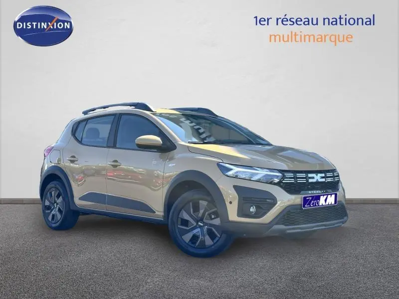 Vue 3/4 avant droit de la Dacia Sandero Stepway beige Safari avec barres de toit et jantes foncées.