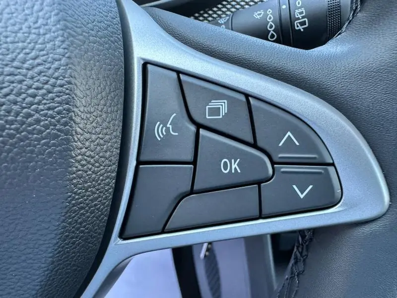 Gros plan sur les commandes noires du volant côté gauche de la Dacia Sandero beige Safari 2025.