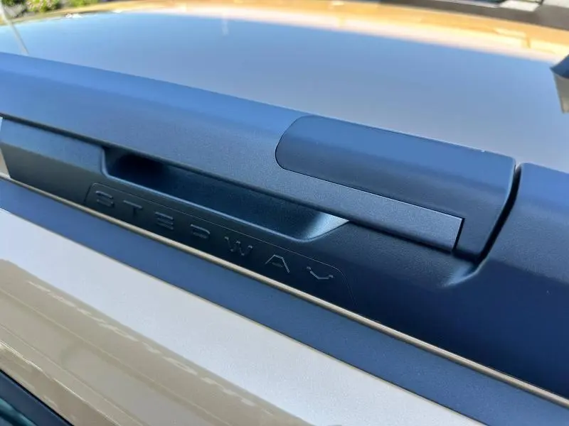 Gros plan sur la barre de toit noire avec inscription Stepway sur la Dacia Sandero beige Safari, vue de dessus.