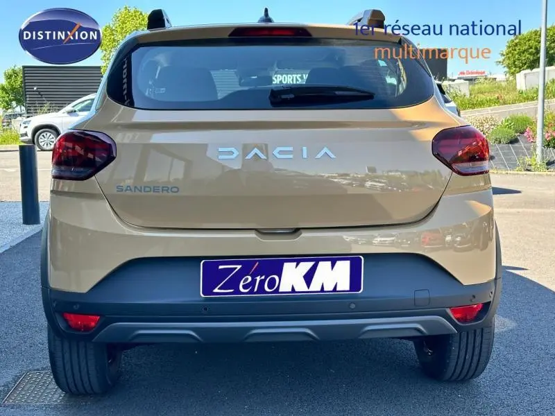 Vue arrière d'une Dacia Sandero beige Safari 2025 avec feux rouges et logo DACIA bien visibles.
