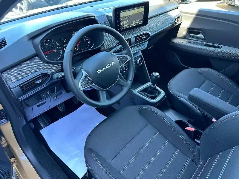 Vue intérieure côté conducteur de la Dacia Sandero beige Safari 2025, volant multifonction et boîte manuelle visibles.