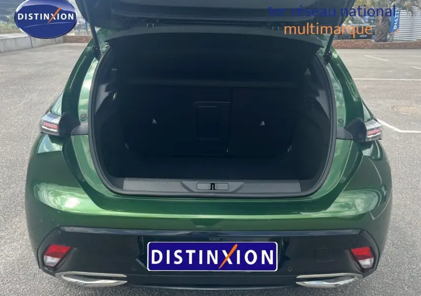 Vue arrière ouverte sur le coffre d'une Peugeot 308 2024 vert olivine métal, avec feux arrière et double sortie d'échappement visibles.