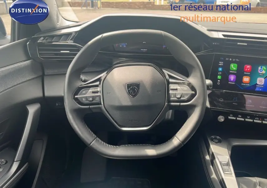 Vue intérieure centrée sur le volant cuir noir et l'écran tactile du tableau de bord de la Peugeot 308 2024.