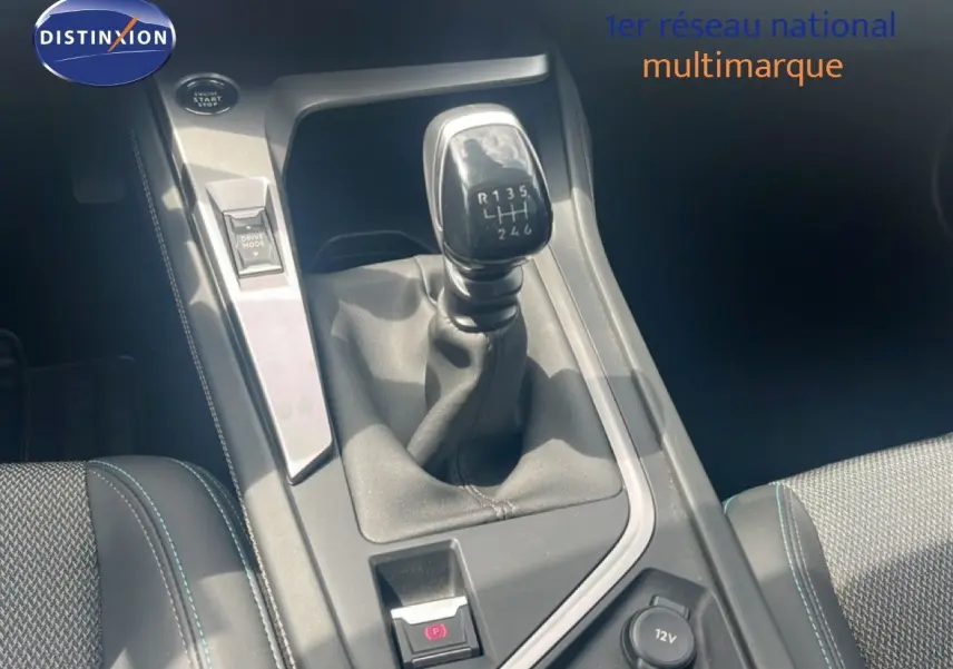 Gros plan sur le levier de vitesse manuel de la Peugeot 308 2024, intérieur gris avec coutures bleues, bouton Drive Mode visible.