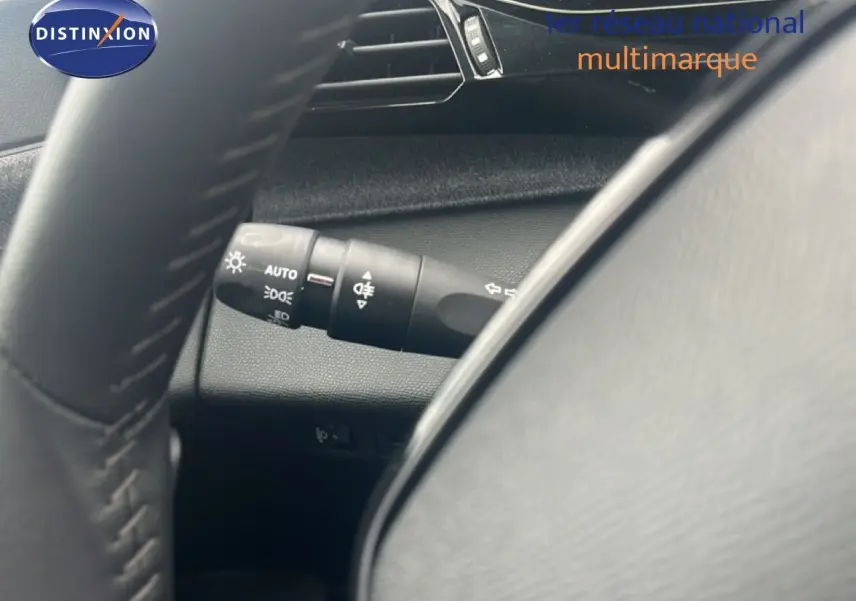 Gros plan sur la commande des feux et clignotants à gauche du volant d’une Peugeot 308 2024, intérieur gris noir.