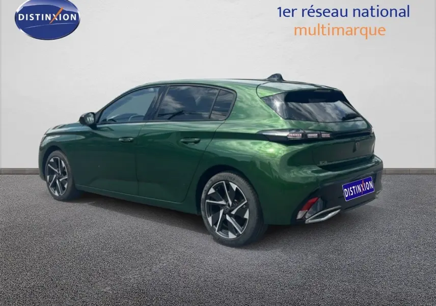 Vue 3/4 arrière droite d'une Peugeot 308 2024 vert olivine métal avec jantes alliage et vitres teintées.
