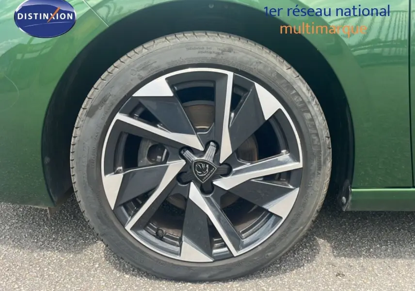 Gros plan sur la roue avant gauche d’une Peugeot 308 2024 vert olivine métal avec jante alliage noire et argent.