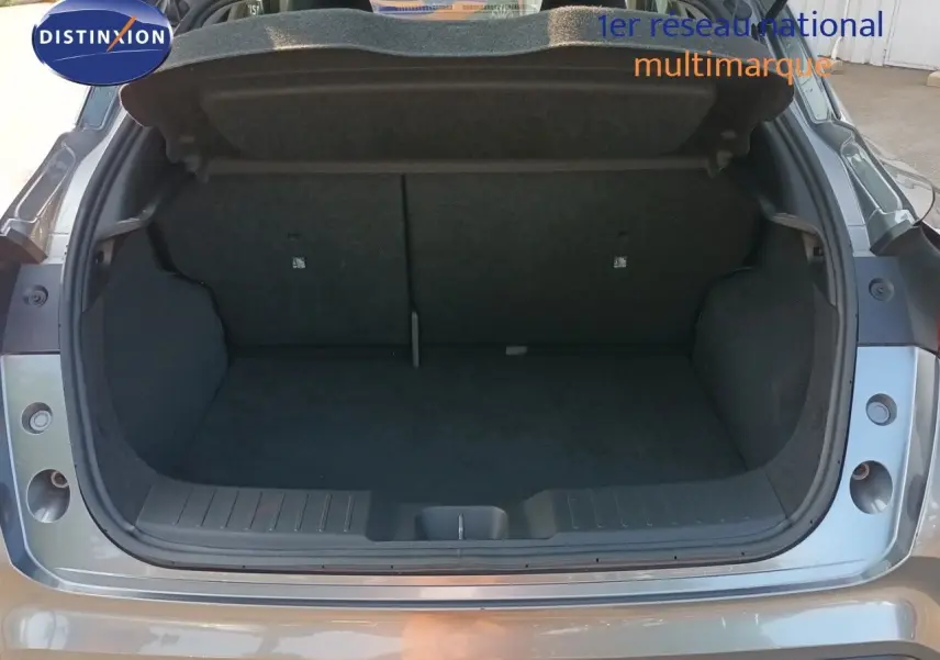 Coffre ouvert vu de l'arrière d'un Nissan Juke 2025 gris squale métal, intérieur de coffre spacieux et propre.
