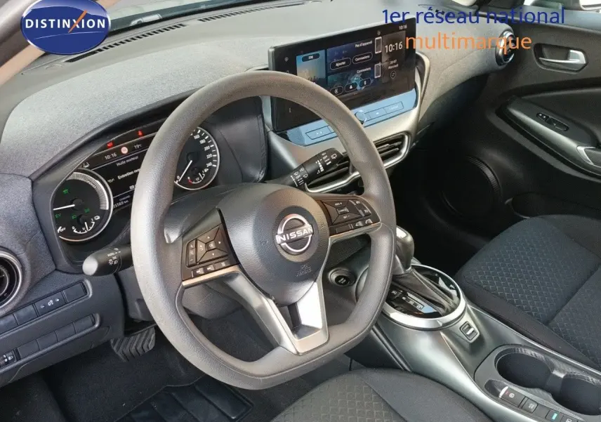 Vue intérieure centrée sur le volant et tableau de bord du Nissan Juke Hybrid 2025 avec finition tissu noir et écran tactile.