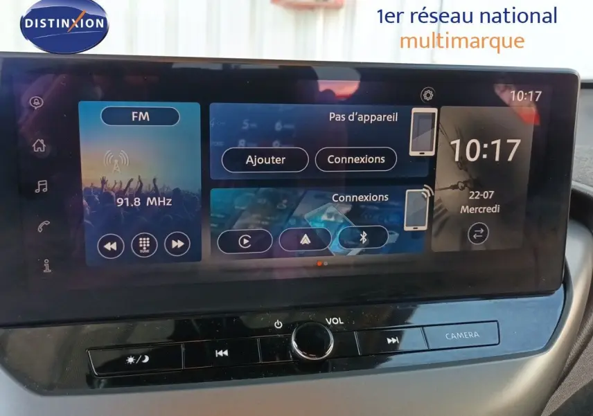 Écran tactile central du Nissan Juke Hybrid 2025, affichant radio FM et options de connexion, vue intérieure frontale.