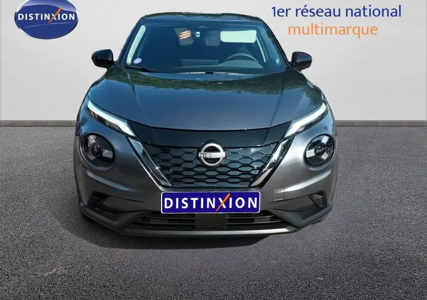 Vue frontale d’un Nissan Juke hybride gris squale métal avec calandre en nid d’abeille et phares ronds distinctifs.