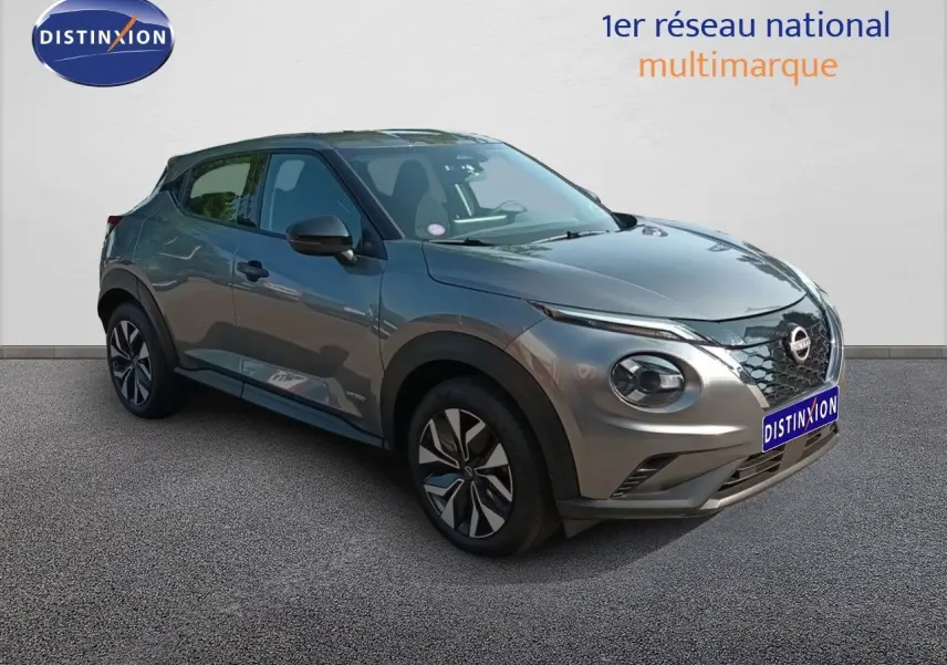 Nissan Juke Hybrid gris squale métal vu en 3/4 avant droit, avec jantes distinctives et calandre noire.