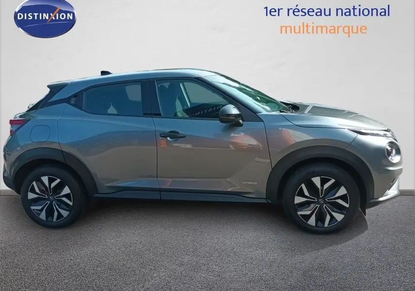 Vue de profil côté gauche d'un Nissan Juke hybride gris squale métal avec jantes distinctives et lignes modernes.