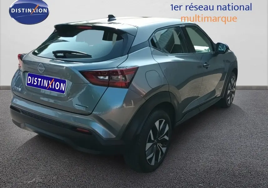 Vue 3/4 arrière droite du Nissan Juke Hybrid 2025 en gris squale métal avec jantes distinctives et feux arrière LED.